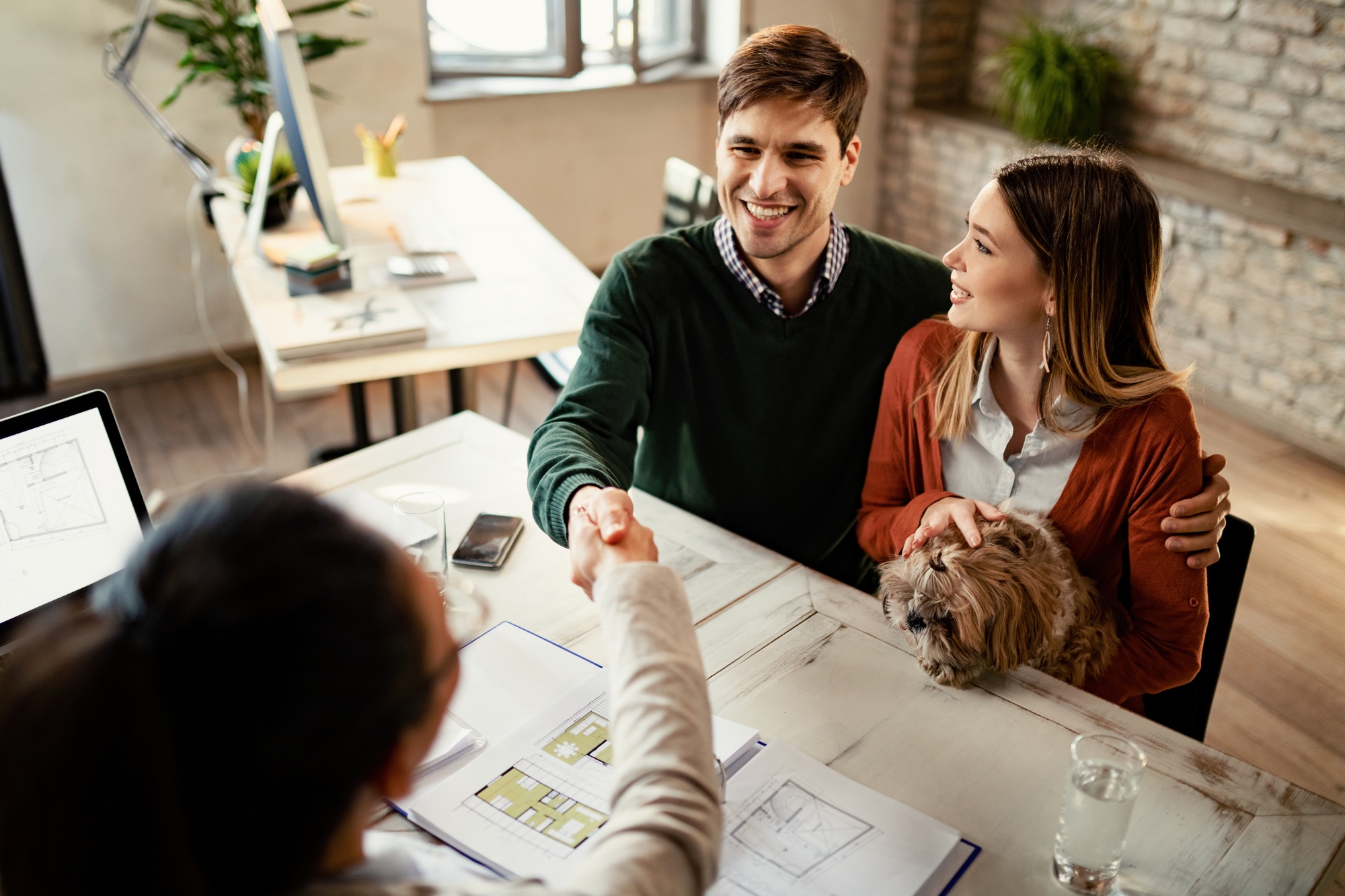 Young happy couple closing a deal with real estate agent.